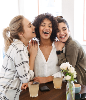 Group of diverse women smiling together while holding yoga mats, representing community and connection.