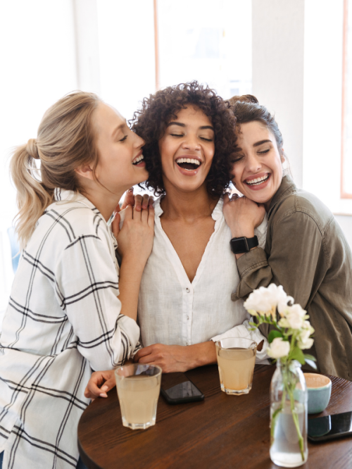 Group of diverse women smiling together while holding yoga mats, representing community and connection.
